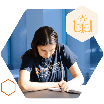A student sitting at a desk and writing in a notebook